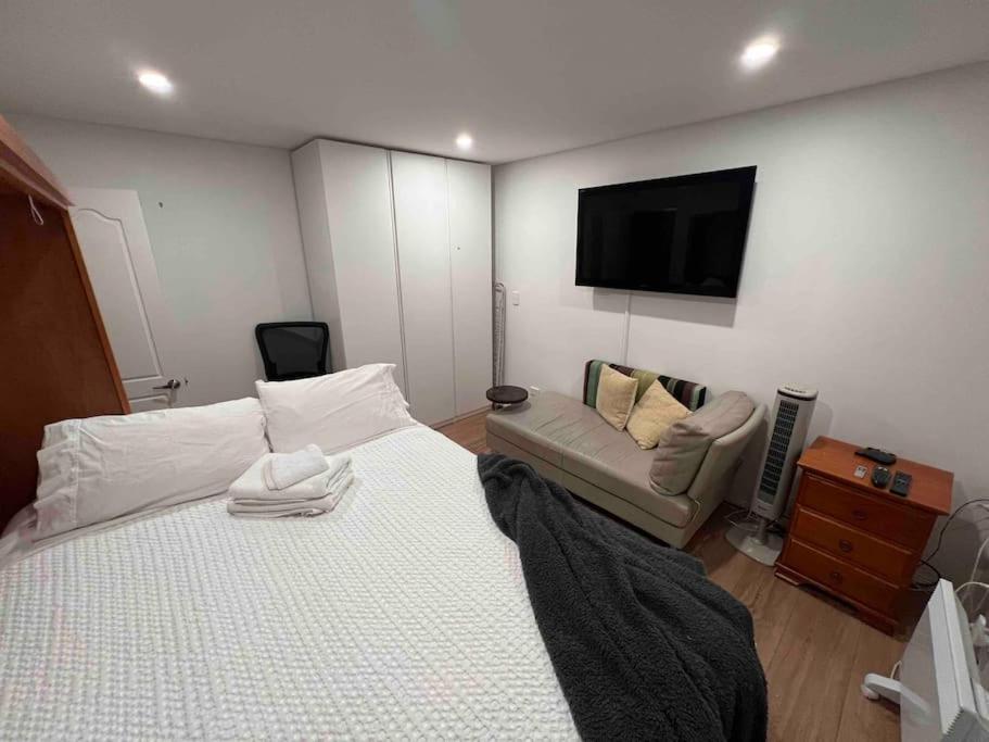 Private 1 bedroom apartment near beach and shops في سيدني: غرفة نوم بسرير واريكة وتلفزيون بشاشة مسطحة