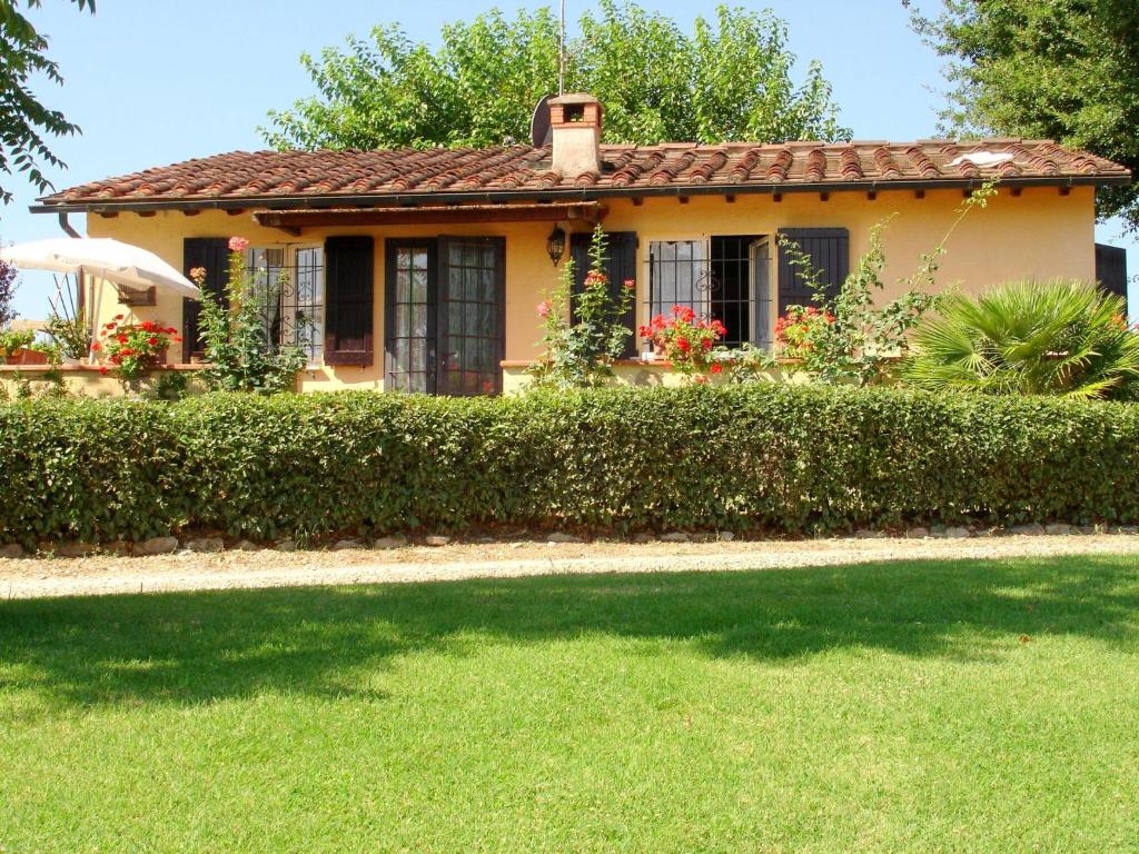 una pequeña casa amarilla con un patio verde en Surrounded by the beautiful sloping Tuscan landscape, en Casole dʼElsa