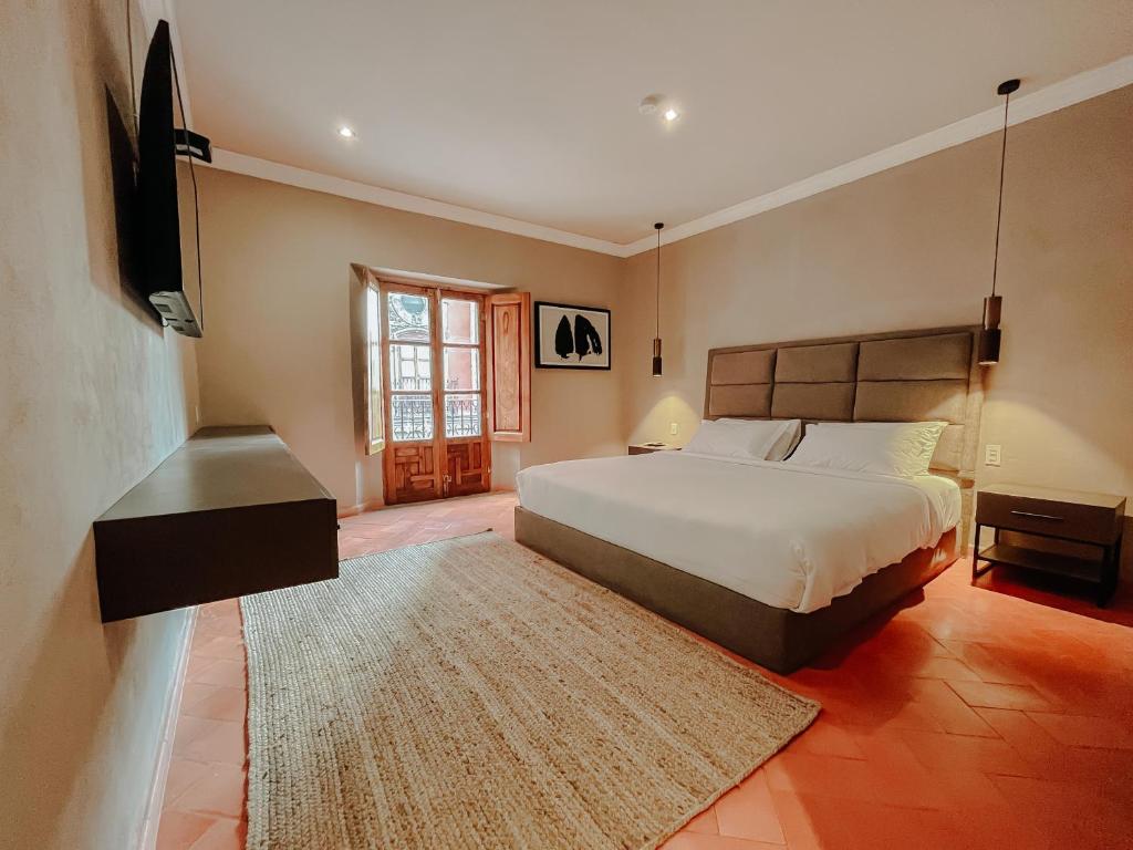 una camera con letto, TV e tappeto di Mikaella Hotel a San Miguel de Allende