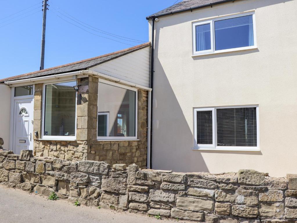 a house with a stone wall in front of it at Island View in Amble