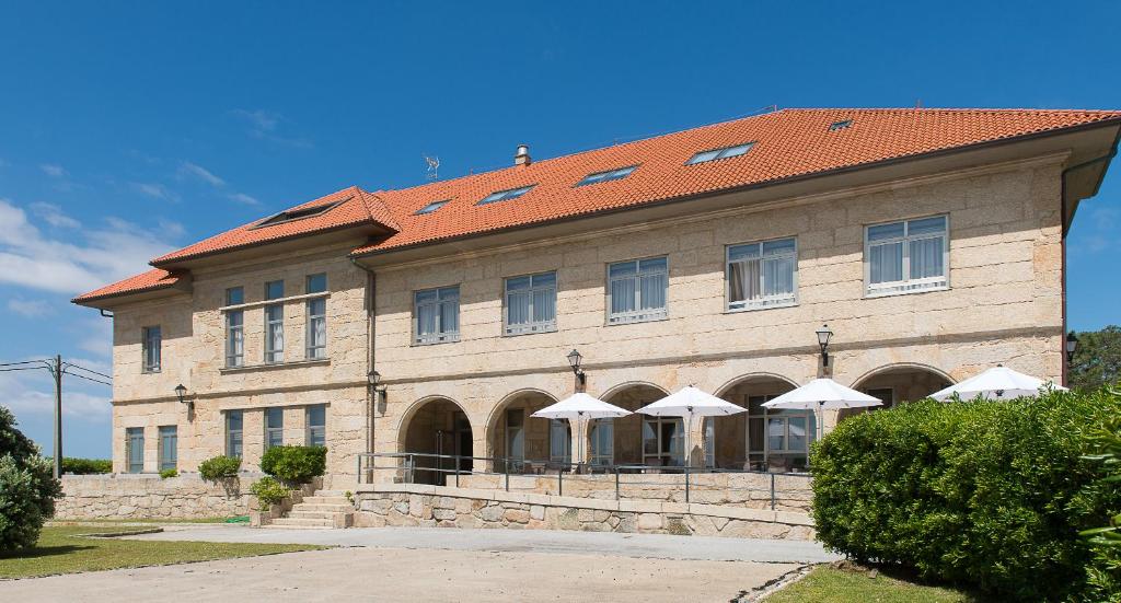 a large building with umbrellas in front of it at Pousada A Lanzada in A Lanzada