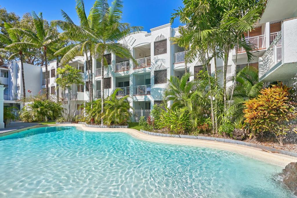 een zwembad voor een gebouw met palmbomen bij Alassio Beachfront Apartments Palm Cove in Palm Cove