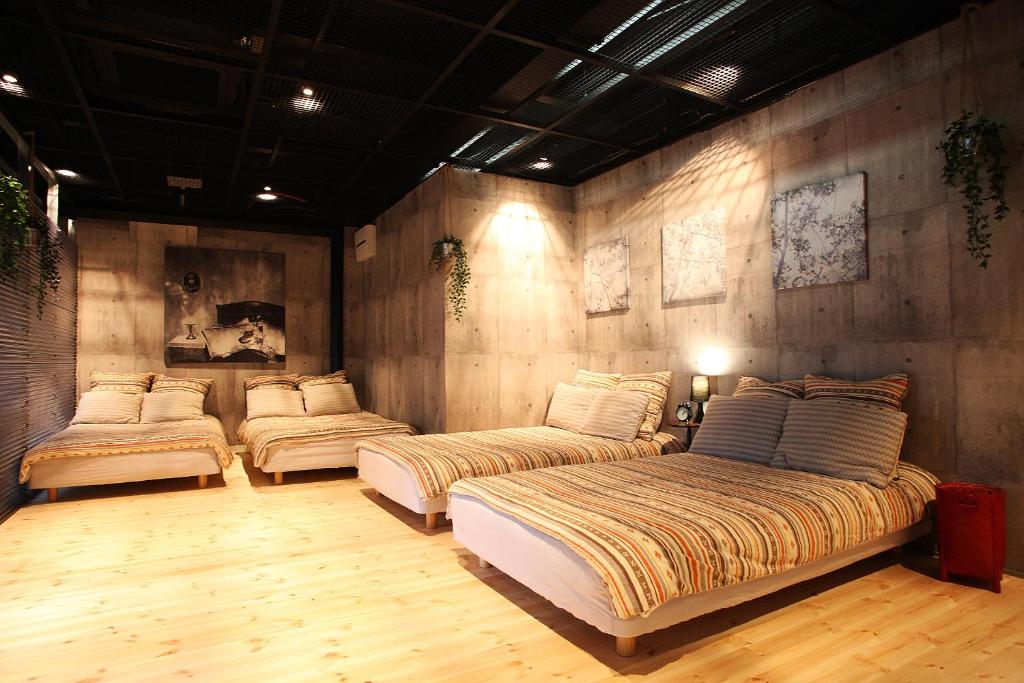 a bedroom with three beds in a room at Kazemachigusa INN in Osaka