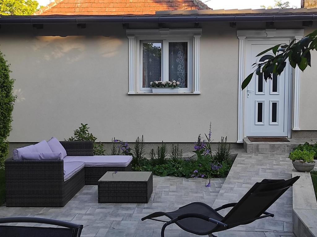 eine Terrasse mit einem Sofa, einem Stuhl und einem Fenster in der Unterkunft Garden Home in Törökbálint