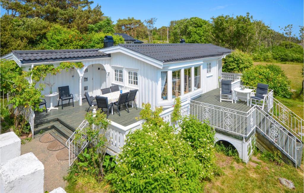 a white house with a deck with a table and chairs at Beach Front Home In Frvik With House Sea View in Arendal