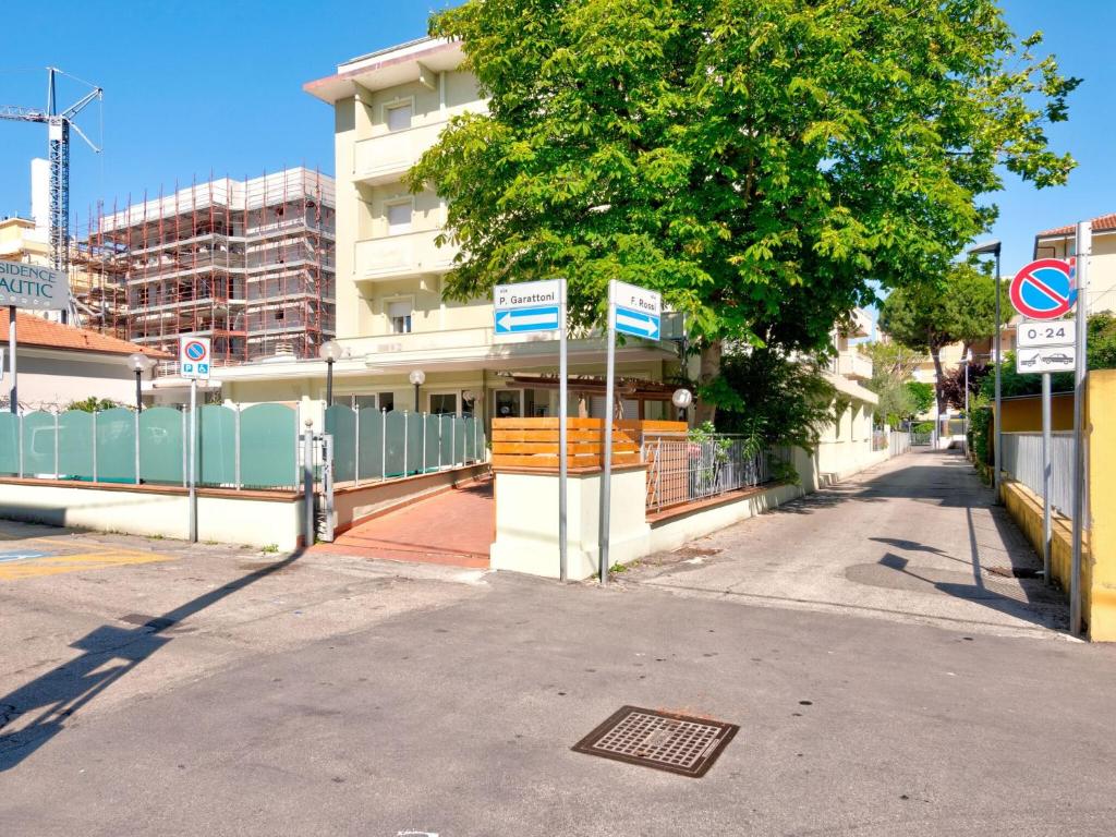 uma rua com um edifício e uma árvore e placas de rua em Comfy Apartment near Rimini Adriatic Coast with a Sea View em Rimini