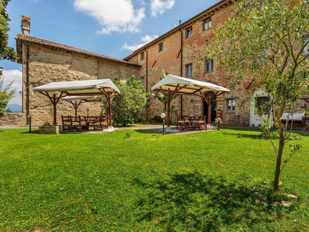 einen Garten mit Tischen und Sonnenschirmen vor einem Gebäude in der Unterkunft Rustic Holiday Home in Citt di Castello with Swimming Pool in Città di Castello