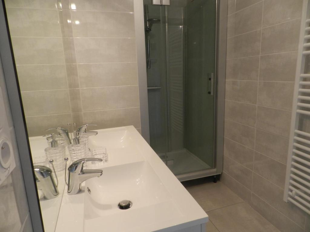 uma casa de banho com um lavatório e um chuveiro em Gîte Utah em Saint-Laurent-sur-Mer