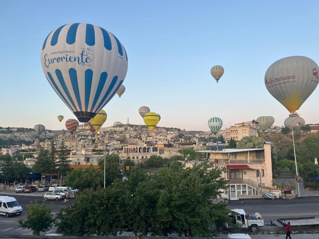 a group of hot air balloons flying over a city at Adventure Inn Cappadocia in Göreme