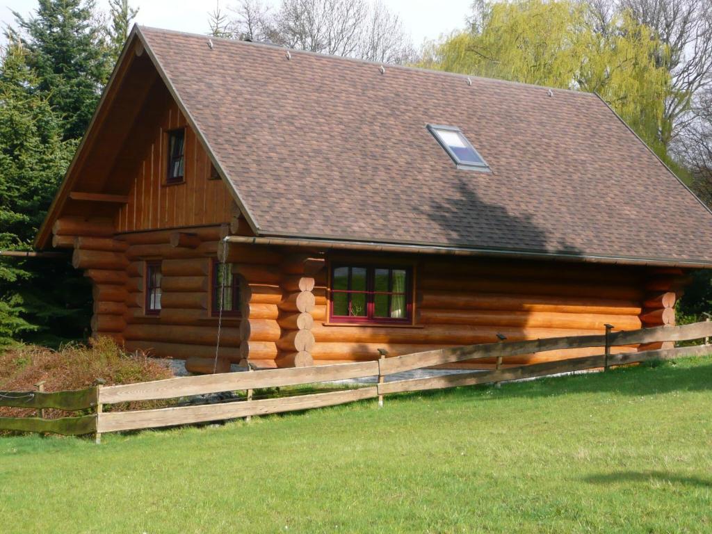 una cabaña de madera con una valla delante en Cozy wooden house in Waltershausen near the forest, en Emsetal