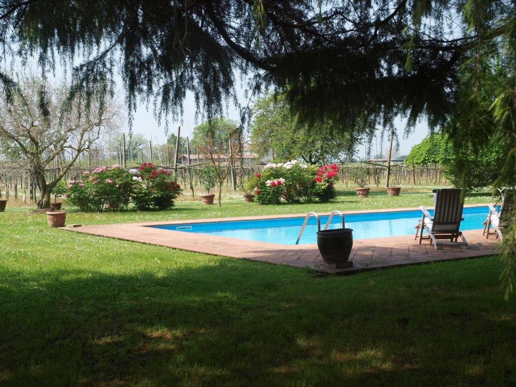 a swimming pool in a yard with two chairs and flowers at Elegant Holiday Home in Faenza with Garden and Pool in Faenza
