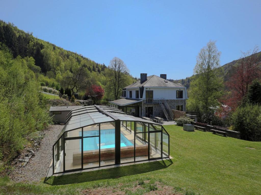 a glass house with a swimming pool in a yard at Modern Mansion in Vielsalm with Sauna and Private Pool in Vielsalm