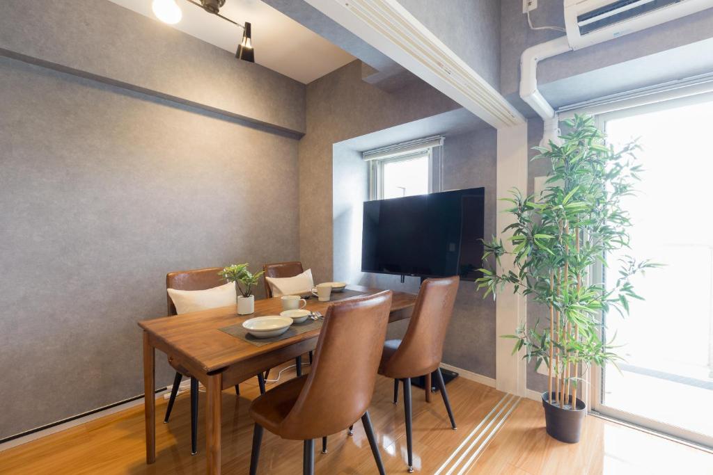 a dining room with a table with chairs and a television at Residence Hotel Hakata 8 in Fukuoka