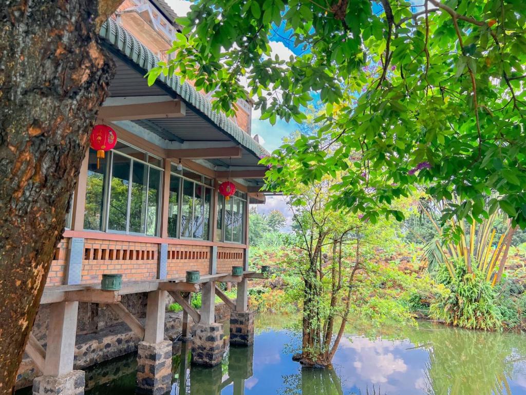 une maison avec un pont sur un étang dans l'établissement Homestay tay, à Xã Trảng Bôm