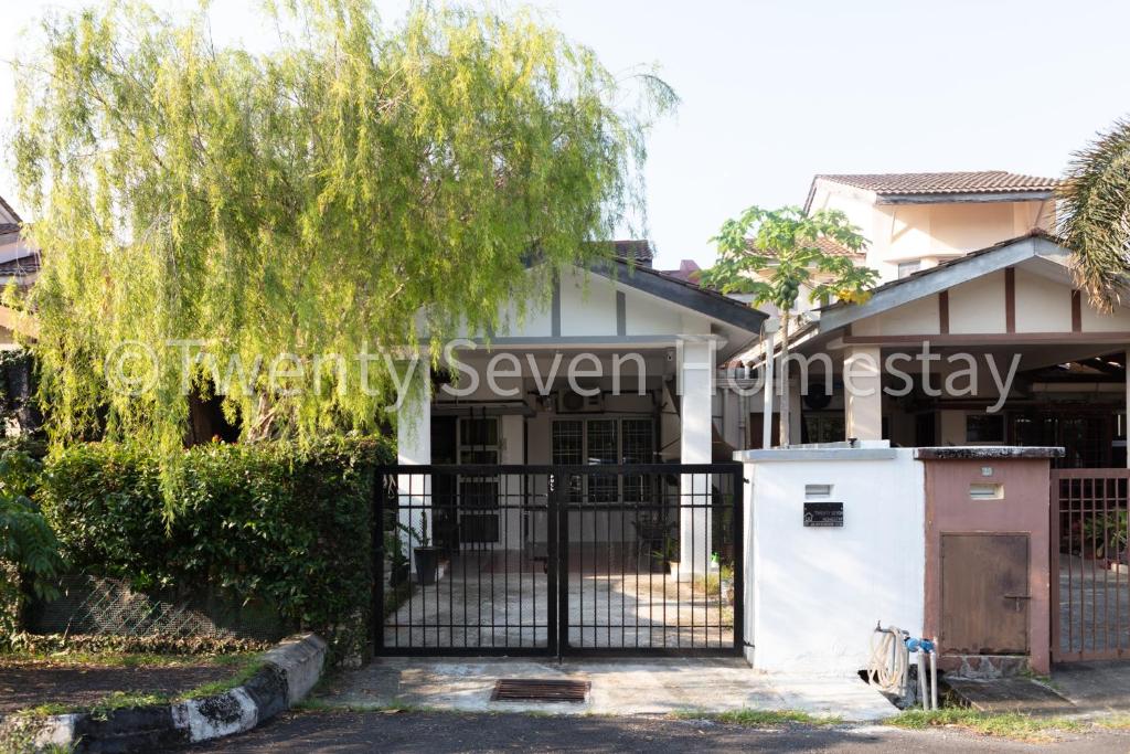 a house with a gate and a tree at Twenty Seven HomeStay in Cheras