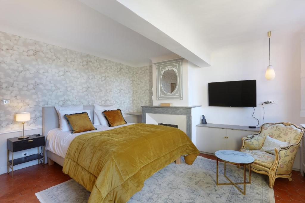 - une chambre avec un lit, une télévision et une chaise dans l'établissement Les suites de Montigny, à Aix-en-Provence