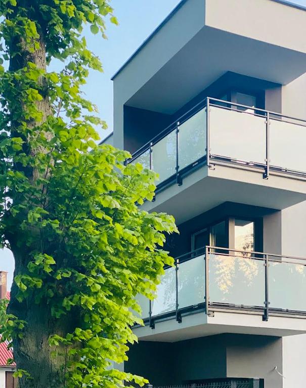 an apartment building with balconies and a tree at Holiday Siesta Pensjonat, Domki z placem zabaw in Rewal