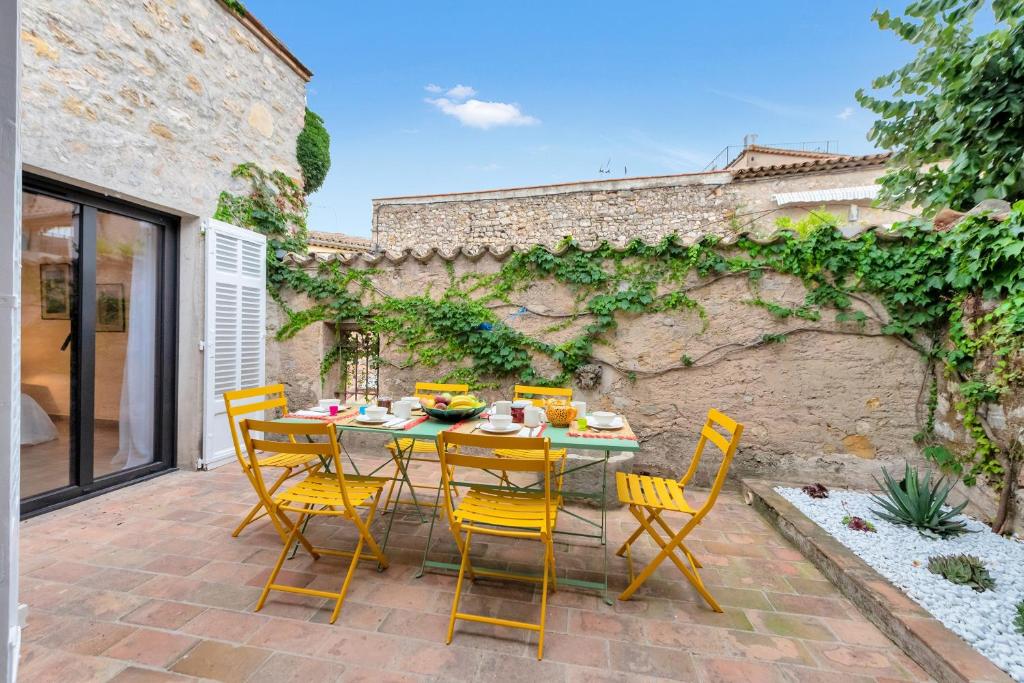 un patio avec des chaises jaunes et une table avec de la nourriture dessus dans l'établissement Lou Amourié - Charmante maison avec terrasse, à Mougins