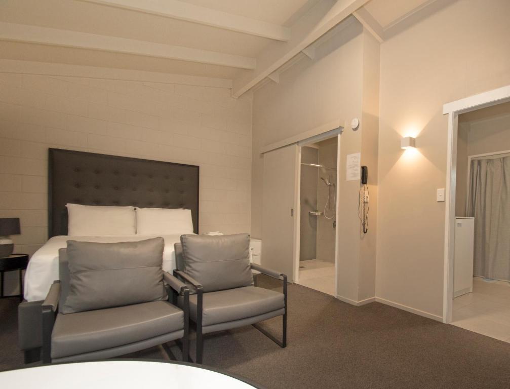 um quarto com uma cama e 2 cadeiras em Middlemore Motel em Auckland