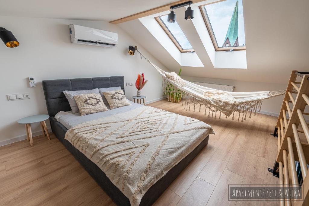 Un dormitorio con una cama y una hamaca. en Apartamenty Yeti & Wilka w Centrum Chorzowa: Wilk, en Chorzów