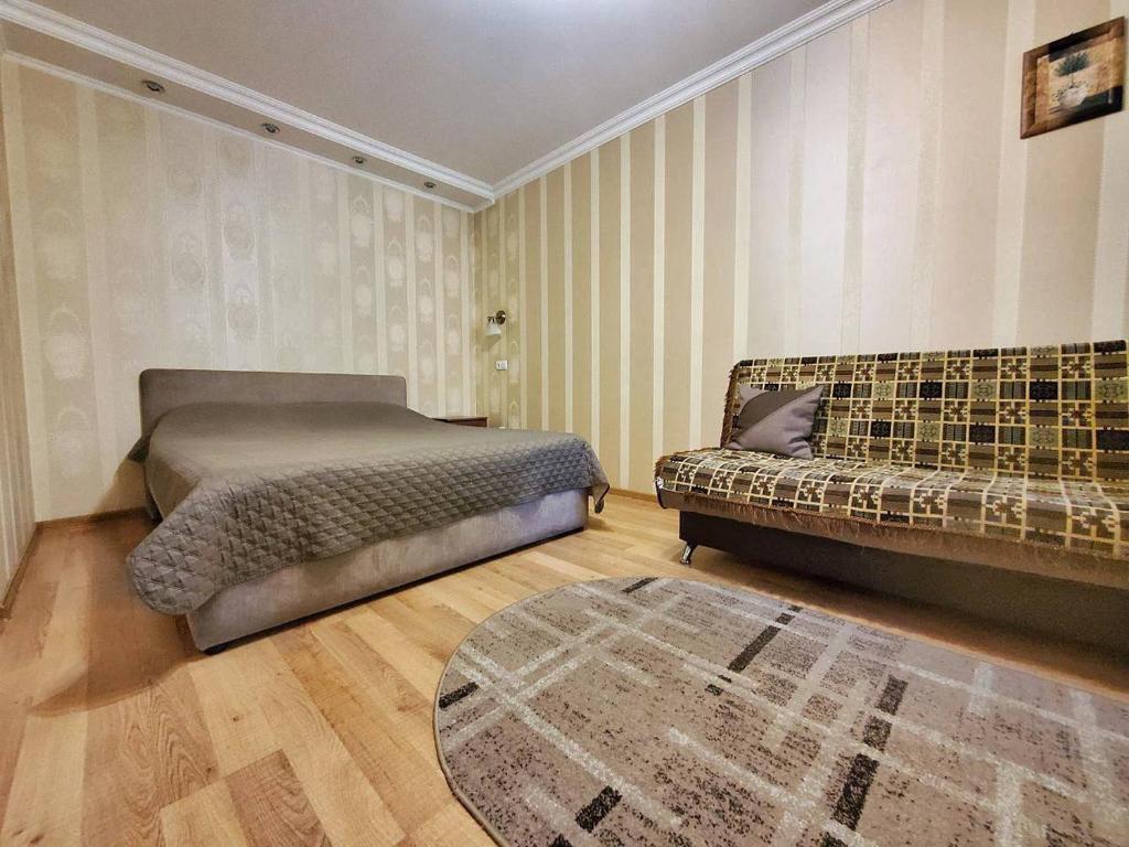1 dormitorio con 2 camas, sofá y alfombra en Новая квартира апартаменты в центре, en Izmaíl