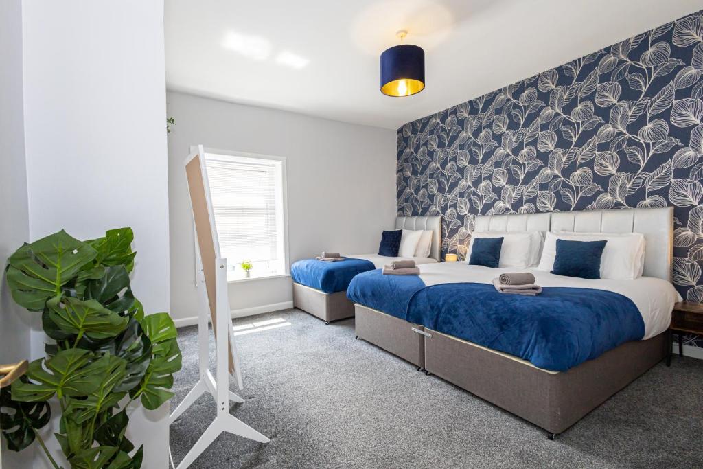 a bedroom with two beds with blue sheets and a wall at Free Parking Leisure Contractor Central in Rishton