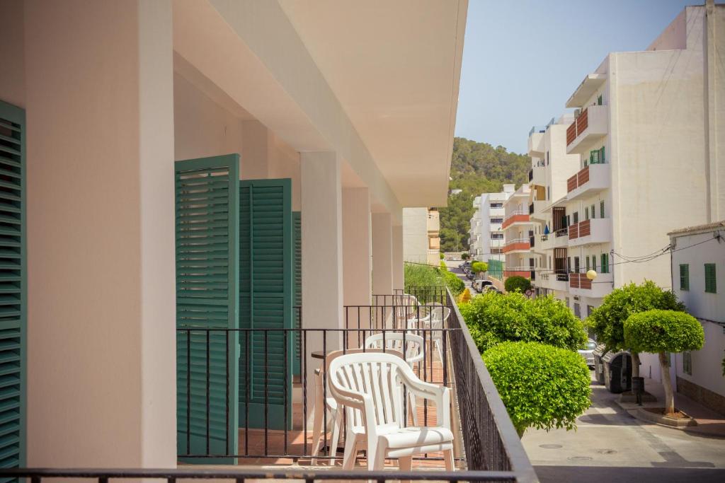 einen Balkon mit zwei weißen Stühlen und einigen Gebäuden in der Unterkunft Hostal Sunset Ibiza in Sant Antoni de Portmany