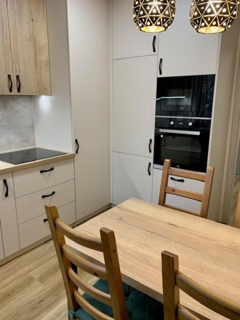a kitchen with a wooden table with chairs and a stove at Apartmán Šnyt Primka in Olomouc
