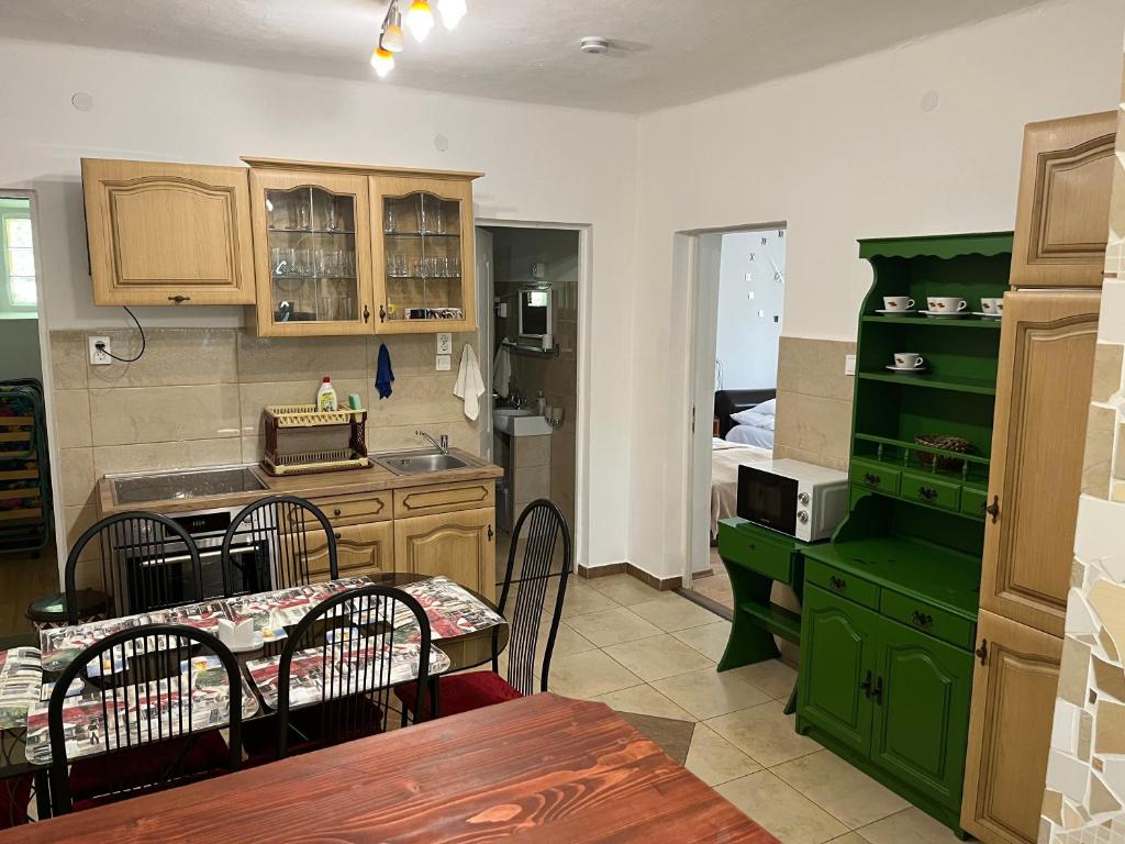 une cuisine avec des placards verts et une table avec des chaises dans l'établissement Francesco Apartmanház, à Velence