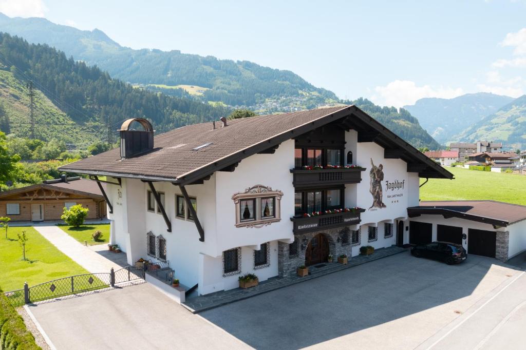 a large white house with mountains in the background at Hotel Garni Jagdhof in Zell am Ziller