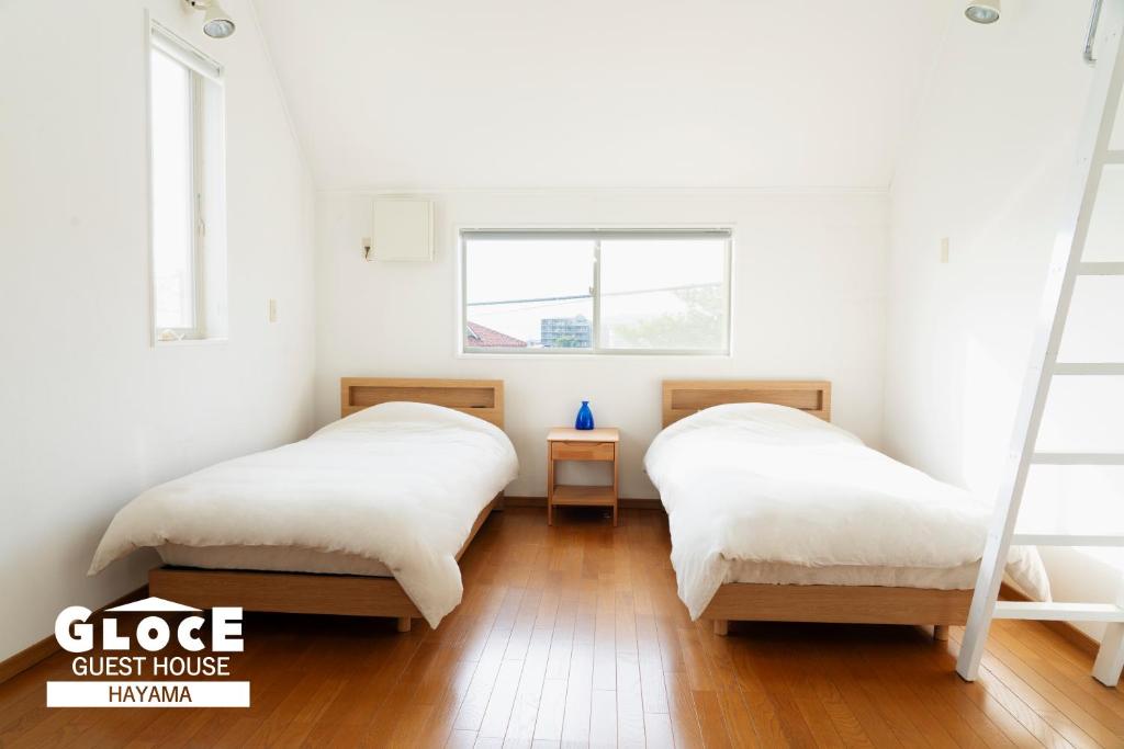 two beds in a room with a window at GLOCE葉山サンセットハウスMORITO l バルコニーから葉山の海と町を一望 小型犬玄関と庭のみアクセス可 in Hayama