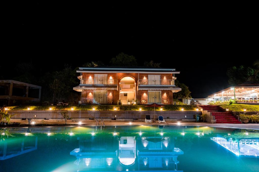 a building with a swimming pool at night at Urmilaa Green County Resort 35 KM From Kolhapur in Kolhapur