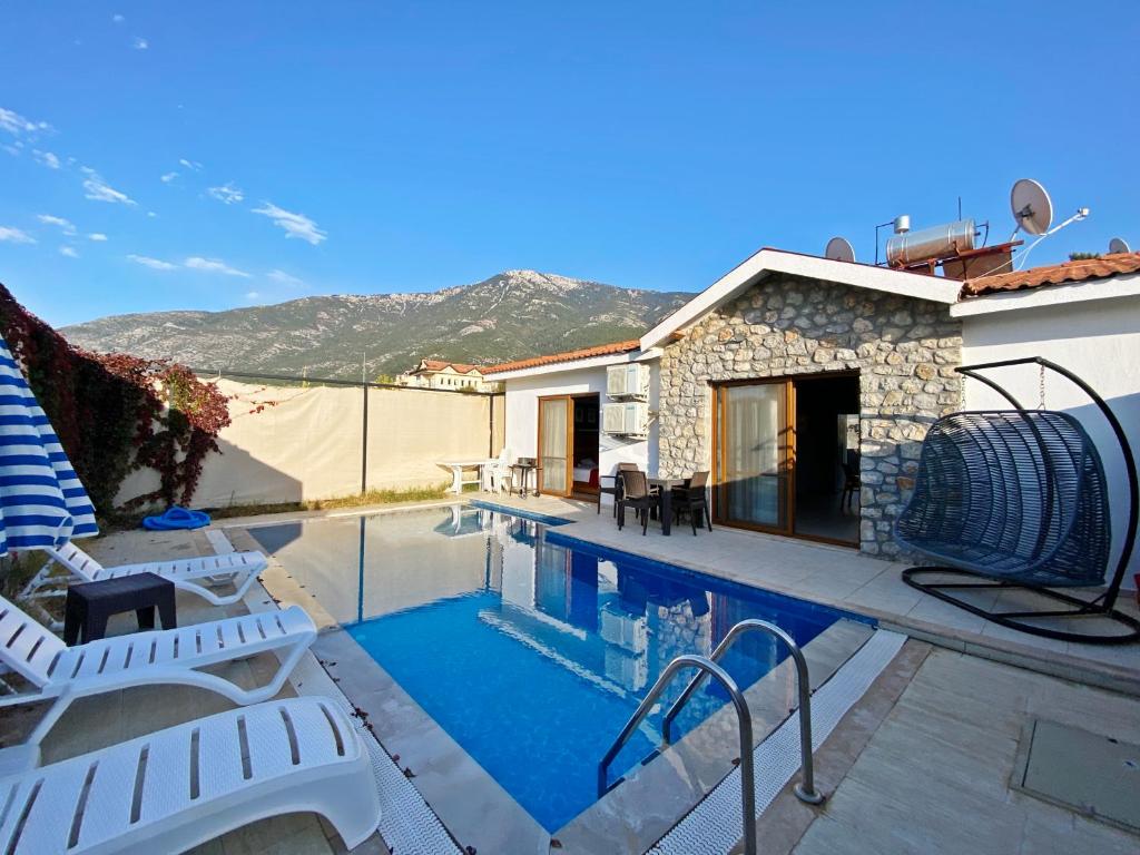 a swimming pool with chairs and a house at Likya Suit B 2+1 Villa, Özel Havuzlu, Fethiye in Fethiye