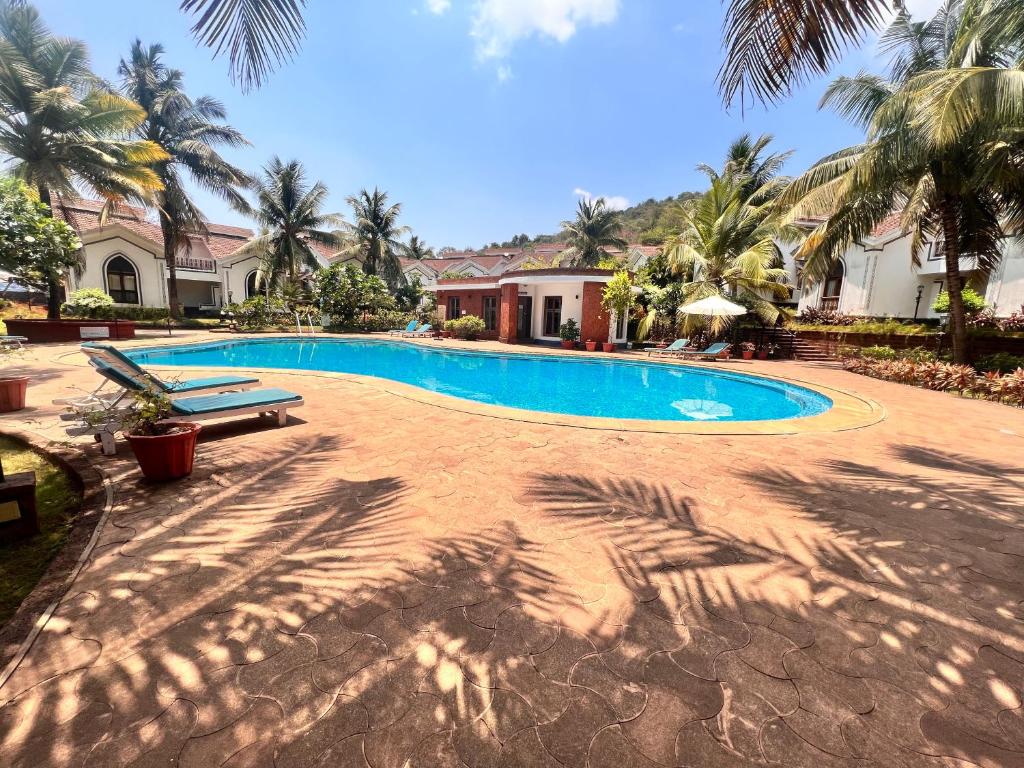 einen Pool in einem Resort mit Palmen in der Unterkunft Riviera Foothills, Arpora in Arpora
