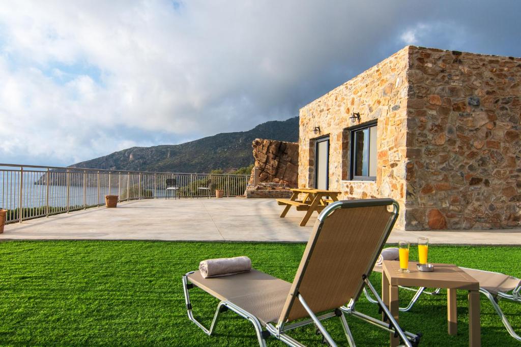 a patio with two chairs and a table on the grass at The Rock *Peaceful Retreat House in Kámbos
