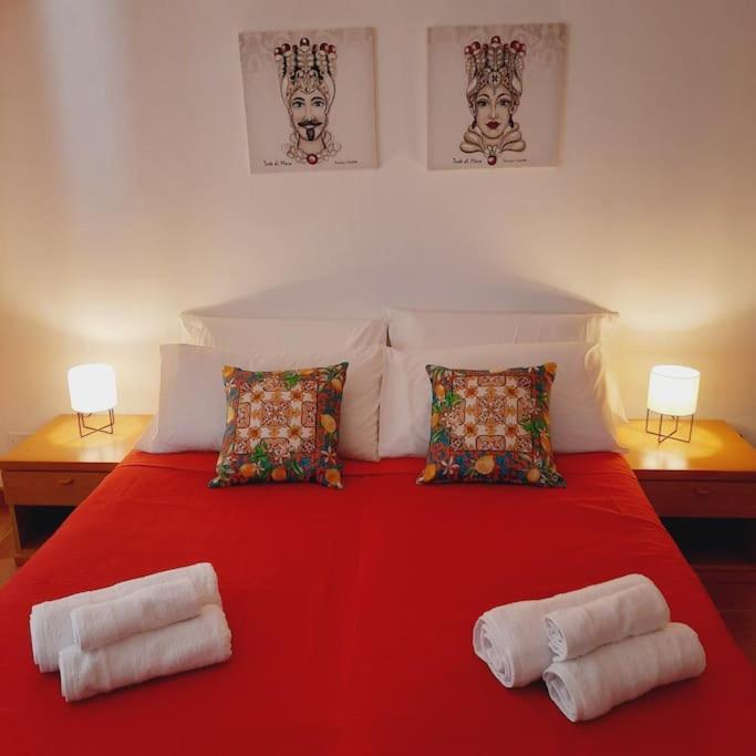 Una cama roja con dos almohadas encima. en La Rosa dei venti en Calatafimi