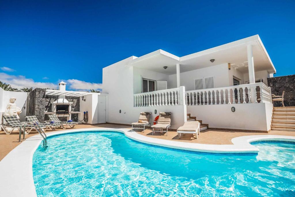 a villa with a swimming pool in front of a house at Villa Tian in Puerto Calero