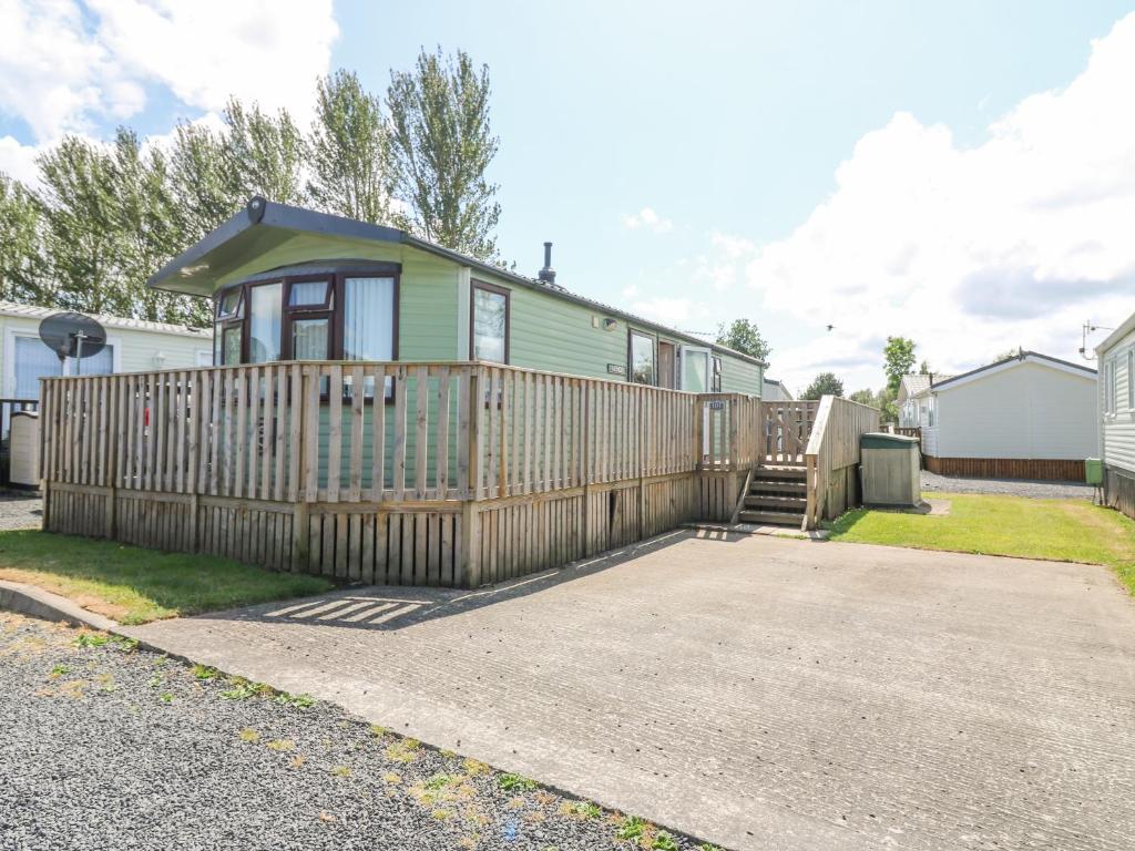 una pequeña casa verde con una valla de madera en Vendee 101 Main en Jedburgh