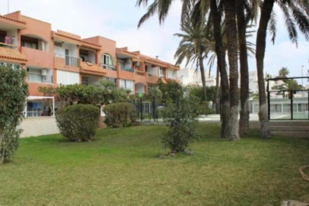 濱海羅克塔斯的住宿－Entremares estudio a 150 metros playa，一座棕榈树的大型公寓楼,位于庭院内