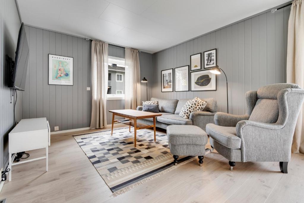 een woonkamer met een bank, stoelen en een tafel bij Mosjøen Apartments Sentrum in Mosjøen