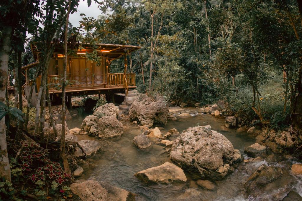 ein Haus inmitten eines Flusses mit Felsen in der Unterkunft Mayana By Blue Space in Banlot