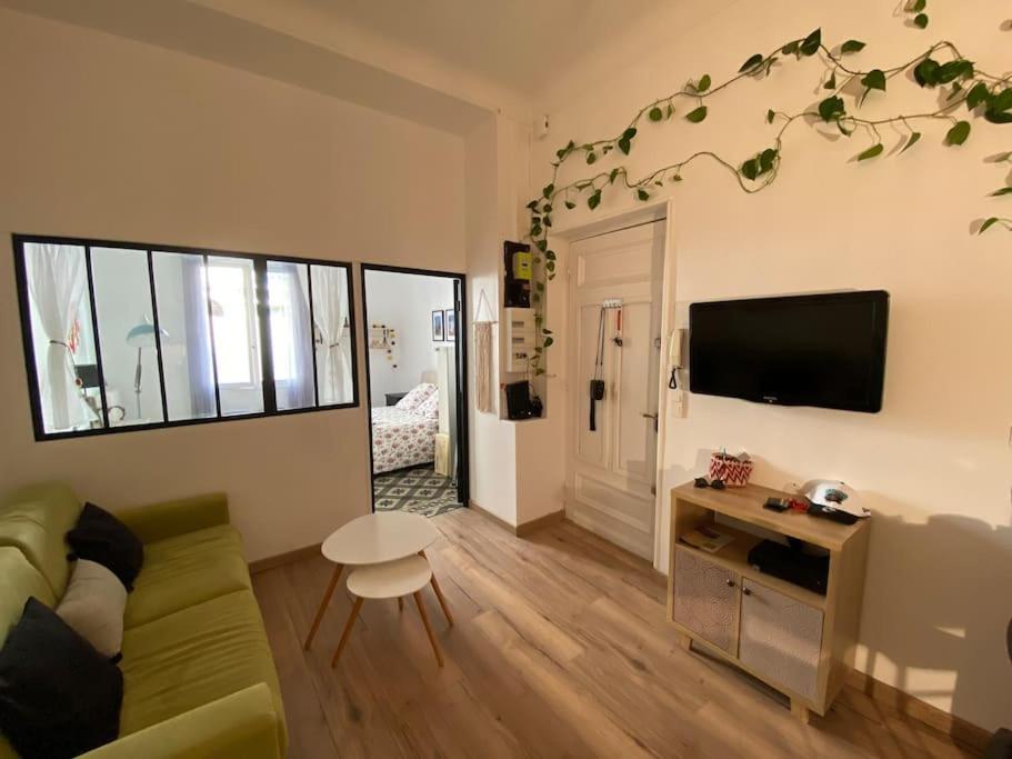 a living room with a green couch and a television at Appartement Proche plages - Parking gratuit in Menton