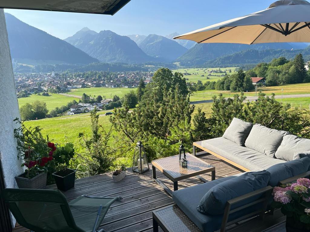 eine Terrasse mit einem Sofa, einem Tisch und einem Sonnenschirm in der Unterkunft Alpenflair Ferienwohnungen Whg. 309 Himmelschrofen in Oberstdorf