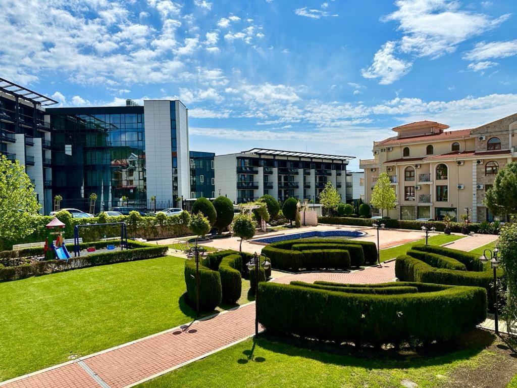 a park with hedges and a building and buildings at Apartment Monica in Sveti Vlas
