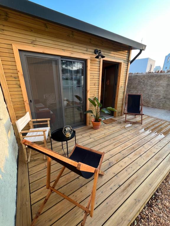 a wooden deck with chairs and a house at Wood11 - Charming TinyHouse in a Lovely Garden in Santa Bárbara de Nexe