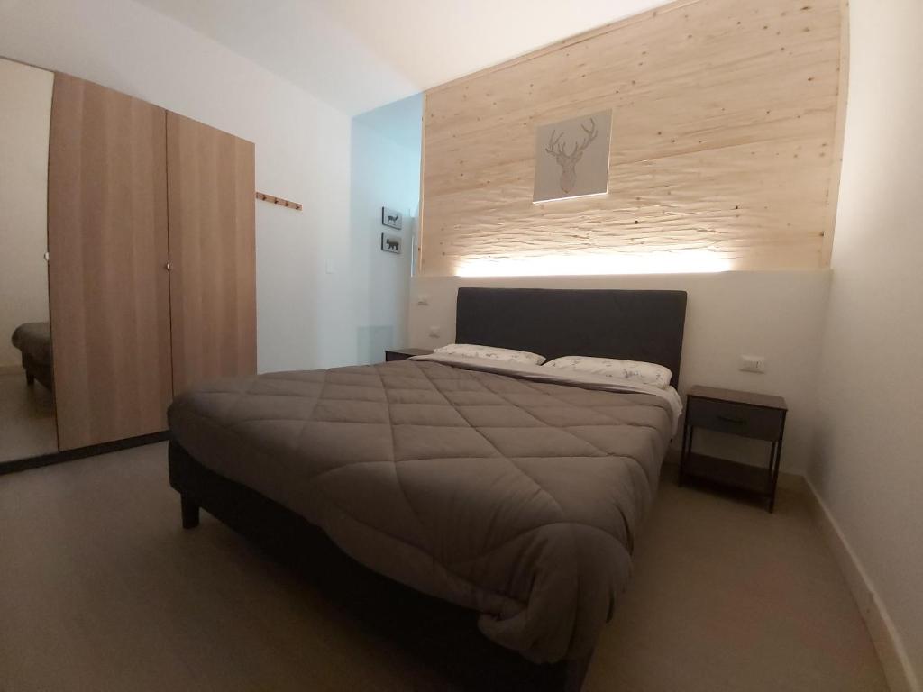 a bedroom with a bed and a wooden wall at CASALIDIA monolocale in Valli del Pasubio