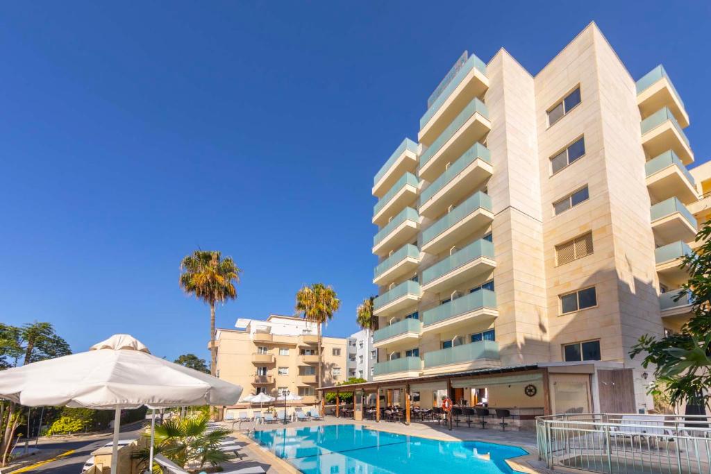 een hotel met een zwembad en een gebouw bij Kapetanios Limassol Hotel in Limassol