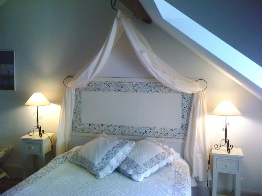 a bedroom with a canopy bed with two lamps at Gîte de la corgette in Saint-Romain