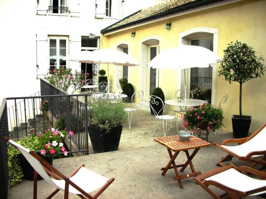 an outdoor patio with chairs and tables and umbrellas at Gîte de la corgette in Saint-Romain