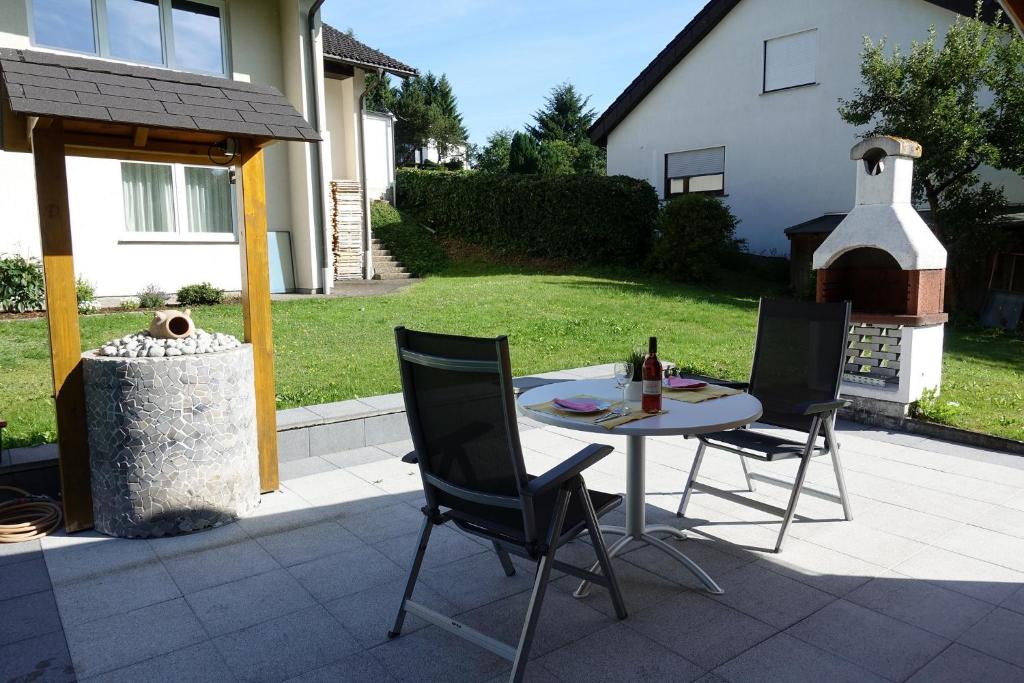 a patio with a table and chairs and a grill at Ferienwohnung Hankeln in Winterberg